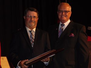 Bryon Hagler, who won 575 games as coach of Licking and Hillcrest high schools, receives an induction plaque from Missouri Sports Hall of Fame President and Executive Director Jerald Andrews on Wednesday, May 27.