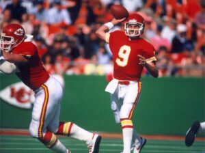Former Kansas City Chiefs player Bill Kenney (9) drops back for a pass during a game.