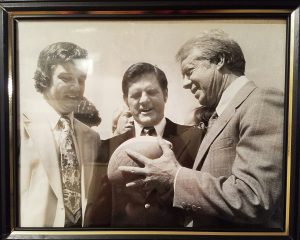 A photo of President Carter accepting a football from Coach Powers.